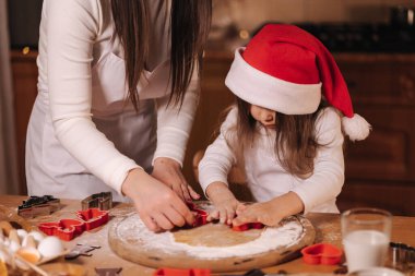 Evde zencefilli ekmek yapıyorum. Annesiyle küçük bir kız zencefilli kurabiye hamuru kesiyor. Noel ve Yeni Yıl gelenekleri. Noel pastanesi. İyi tatiller.