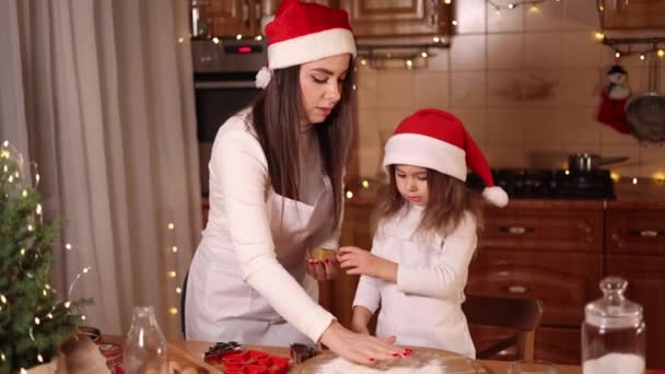 Two girls in santa hat spent time very happy at the kitchen. Christmas holidays — Stock Video