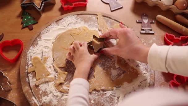 家でジンジャーブレッドを作る。ジンジャーブレッド生地のクッキーを切る女の子。クリスマスと新年の伝統的な概念。クリスマスベーカリー。幸せな休日。トップ表示 — ストック動画