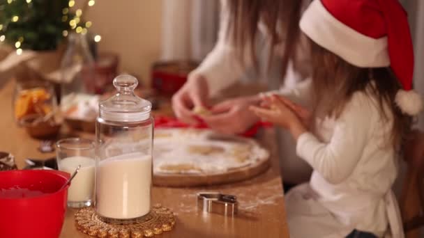 Processo de assar mãe e filha em casa. Massa crua para cozinhar biscoitos de Natal pão de gengibre na mesa de madeira. Luz da vela à noite. Árvore — Vídeo de Stock