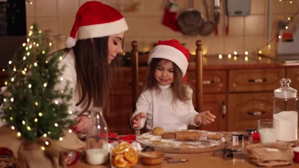 Processus de cuisson maman et fille à la maison. Pâte crue pour la cuisson des biscuits de Noël pain d'épice sur une table en bois. Lumière de bougie à l'heure du soir. Sapin — Video