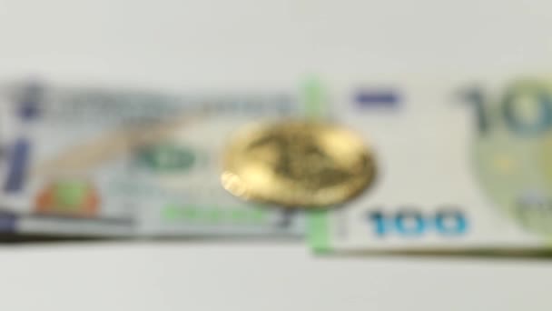 Отменённое видео цифрового криптовалютного золотого биткойна, лежащего на банкнотах США и евро. Разница между виртуальными деньгами и наличными. Концепция новых виртуальных денег — стоковое видео
