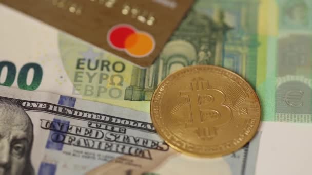 Золотые биткоины размещаются на кредитных картах под банкнотами в долларах США и евро. Концепция криптовалюты. Закрыть — стоковое видео
