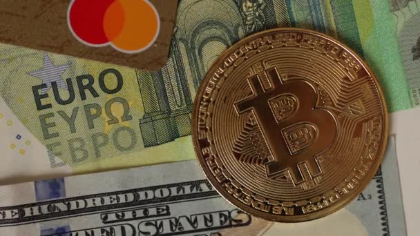 Bitcoin emas ditempatkan pada kartu kredit di bawah uang kertas dolar dan euro AS. Konsep Cryptocurrency. Tutup. — Stok Video