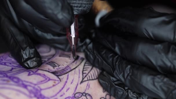Nahaufnahme eines jungen professionellen Tätowierers, der mittels Nadel von einem drahtlosen Tätowiergerät schwarze Tinte in die Haut einbringt. Tätowierung zur Hand — Stockvideo