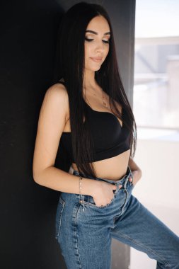 Güzel bir kadının portresi stüdyoda fotoşostur. Kot pantolon ve beyaz gömlekli seksi kız. Çıplak ayaklı kadın. Siyah arkaplan