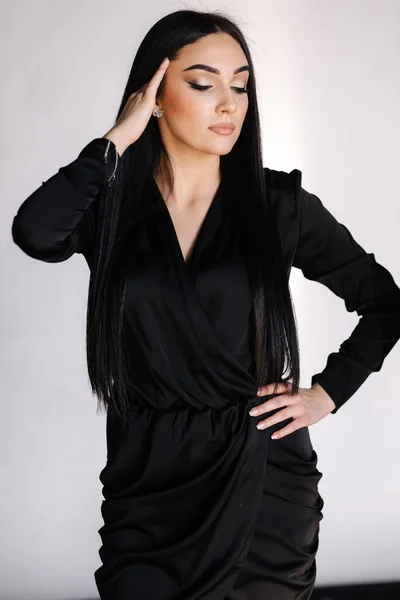 Vacker brunett kvinna i elegant svart klänning. Kvinna med kvällsmakeup. Studio fotografering — Stockfoto