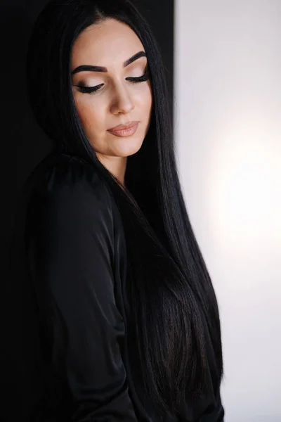 Portrait of gorgeous female in black dress. Brunette woman close her eyes to show make up. Studio photo shoot —  Fotos de Stock