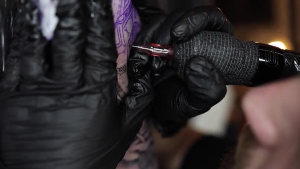 El primer plano de un joven maestro profesional del tatuaje introduce tinta negra en la piel usando la aguja de una máquina de tatuaje inalámbrica. Tatuaje a mano. Vídeo vertical 4K. 50fps — Vídeos de Stock