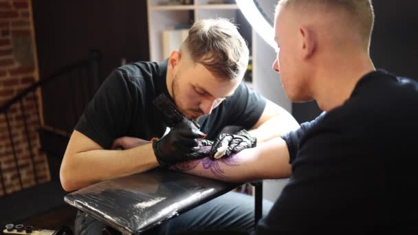 El maestro del tatuaje está tatuando una mano de hombre. Máquina de tatuaje inalámbrica, seguridad e higiene en el trabajo. Primer plano de la obra del artista del tatuaje. Salón del tatuaje — Vídeo de stock