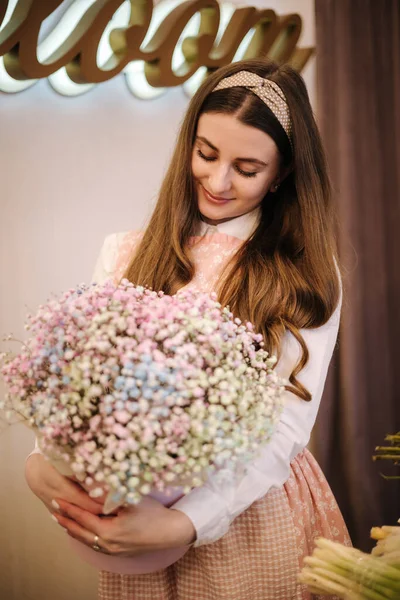 Woman make spring bouquet. Female florist hold beautiful bouquet of spring flowers in pack paper. Beautiful flower composition of gypsophila —  Fotos de Stock