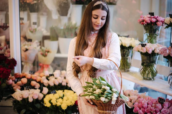 Kadınlar bahar buketi yapar. Dişi Floris bir buket beyaz lale koydu. Güzel bir çiçek kompozisyonu. Taze laleler