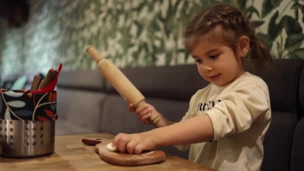 Kleines Mädchen mit Nudelholz zum Pizzabacken zu Hause. Nahaufnahme von rollendem rohen Teig. Heimatstimmung. Vorbereitung auf Feiertage — Stockvideo