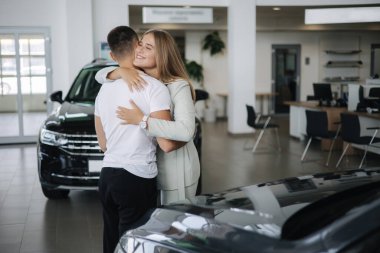 Güzel kadın araba galerisinden araba aldıktan sonra kocasına sarılıyor. Erkek ve kadın yeni araba alırlar. Mutlu çiftin yeni bir aracı var.