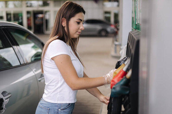 Woman is preparing for refueling at gas station. Female hand filling benzine gasoline fuel in car. Petrol prices concept. Self-service. Fuel shortage in Ukraine