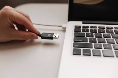 Kadın eli USB adaptörünü dizüstü bilgisayarla kopyalamaya koydu.