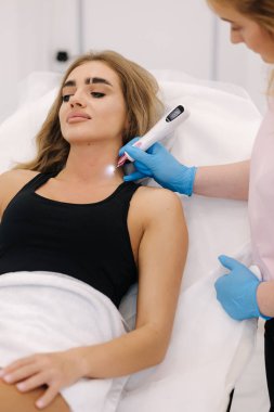 Genç bir kadının boynundaki neoplazmayı azaltan plazma kalem. Zararsız kozmetik tedavi