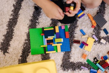 Çocuklar yapıcılık oynar ve parçalardan farklı şekiller toplarlar..