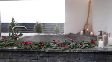 Buharlı demir jakuzi, kışın kaplıca, kar ve dekore edilmiş mumlar. Guelder gülü Noel dalları.