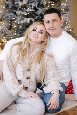 Kocasıyla birlikte evde fotoğrafçıya poz veren muhteşem bir kadın. Noel havası. Işıkların arkaplanı