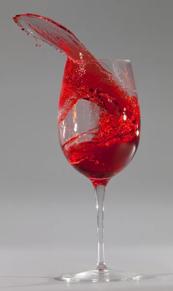 Wine glass with red liquid spill