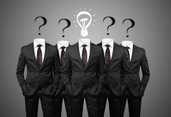 Businesssman with idea standind between other businessmen having questions instead of heads — Stock Photo, Image