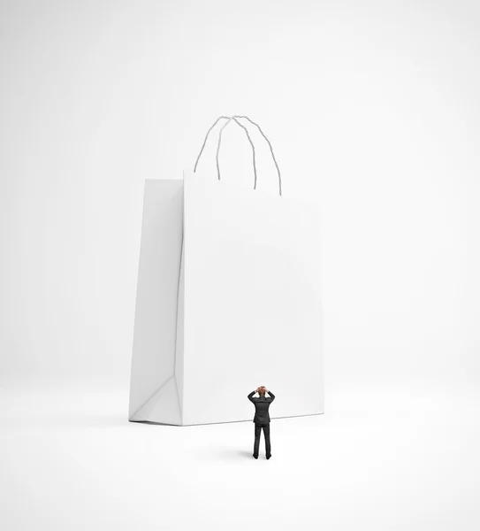 Hombre molesto mirando enorme bolsa de compras en blanco —  Fotos de Stock