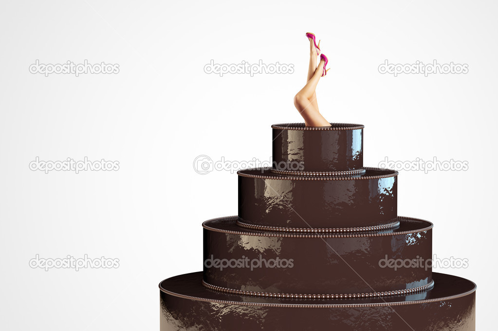 Female legs stick out from a large chocolate cake