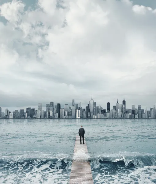 Zakenman kijken naar stad op een pier — Stockfoto