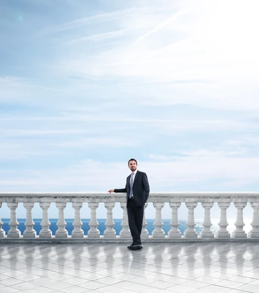 Businessman on column banister — Stock Photo, Image