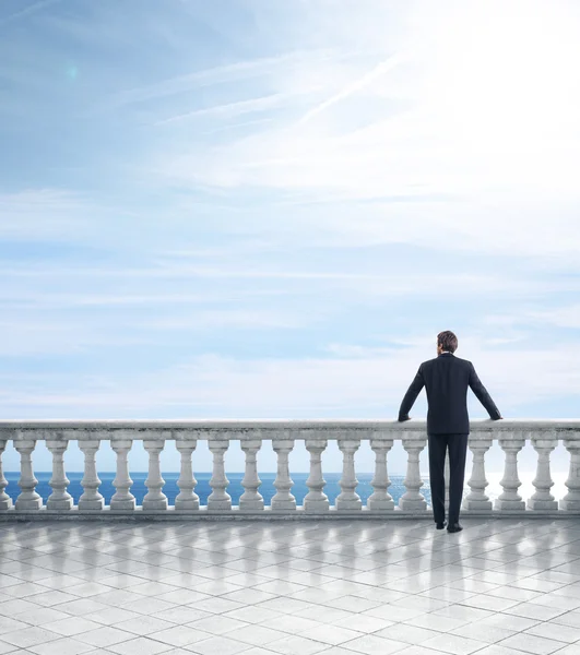 Businessman on column banister — Stock Photo, Image