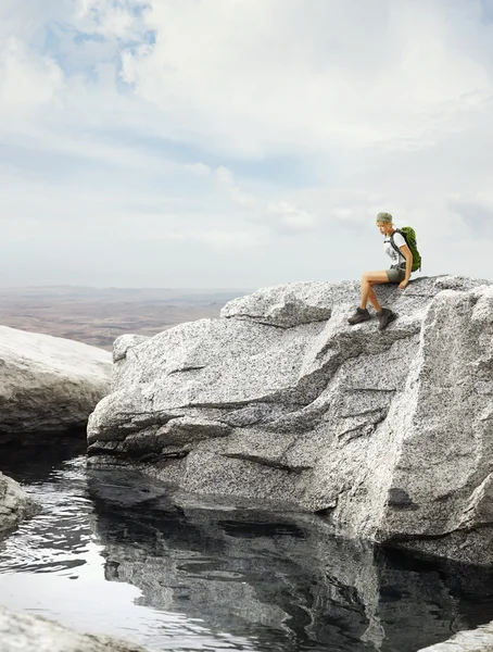 Traveler girl sitting on a rock — Stock Photo, Image