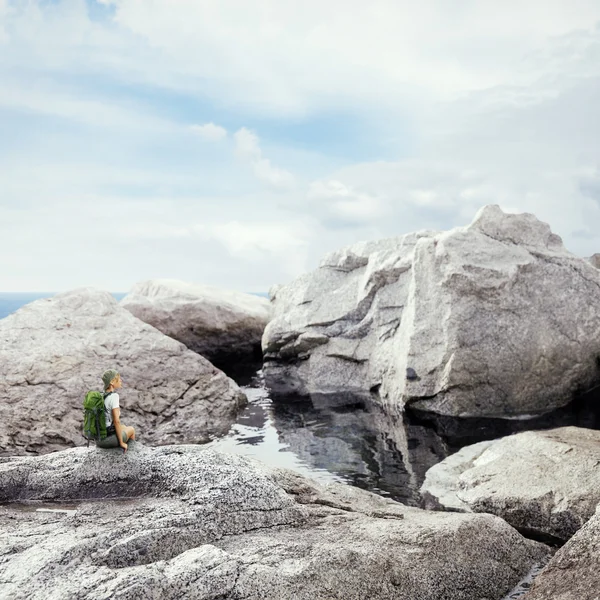 Traveler woman sitting on a rock — Stock Photo, Image