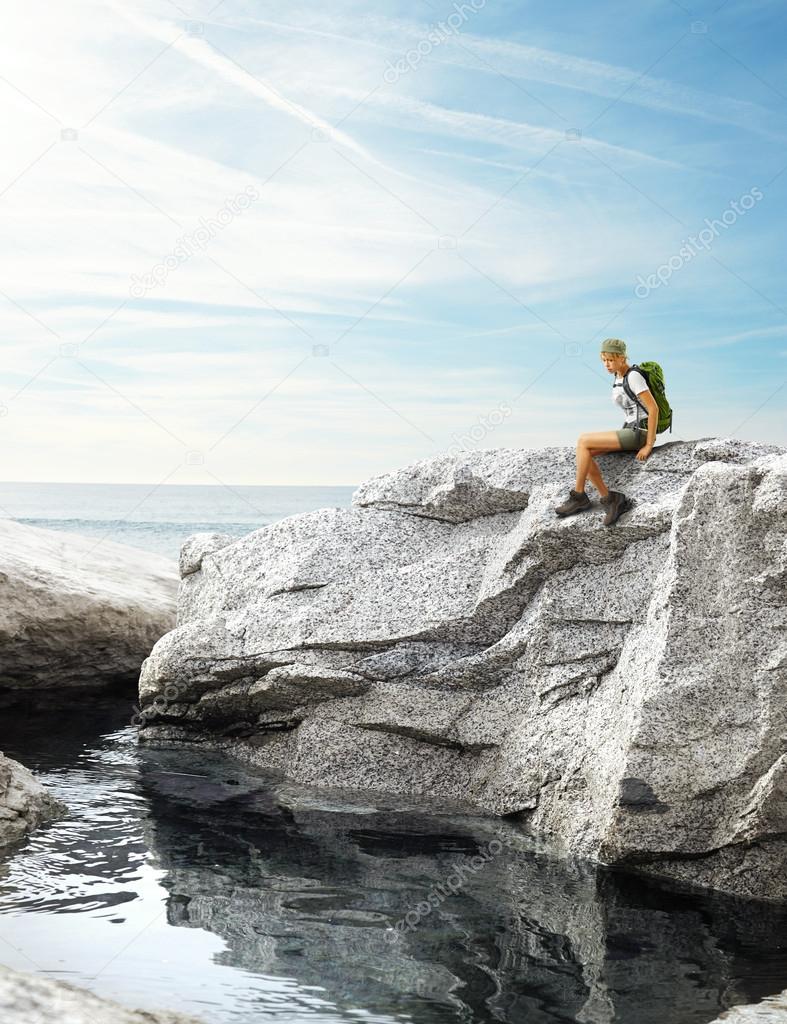 Traveler woman sitting on a rock near sea