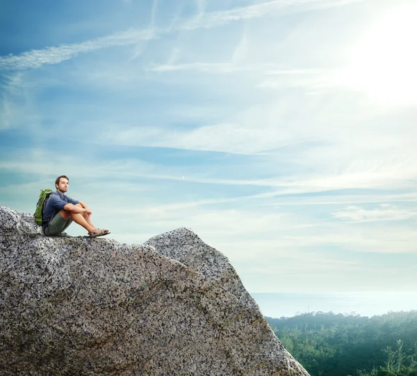 Young man sitting on a rock — Stock Photo, Image