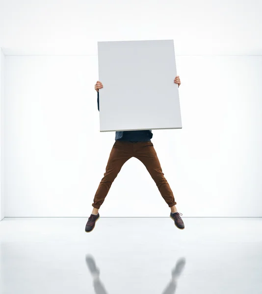 Hombre saltando con cartel en blanco en sus manos —  Fotos de Stock