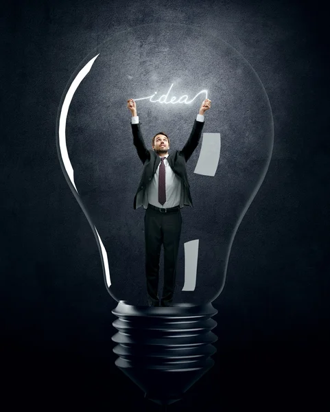Homem segurando ideia luminosa dentro da lâmpada — Fotografia de Stock
