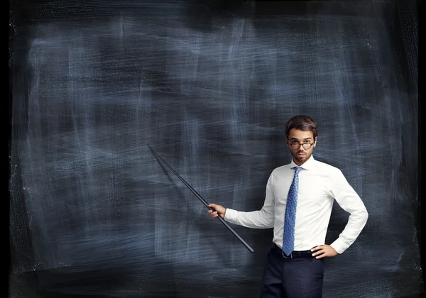 Man with pointer in his hand on black board background — Stock Photo, Image