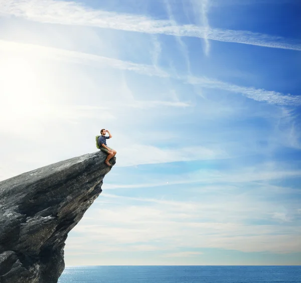 Young man sitting on a peak — Stock Photo, Image