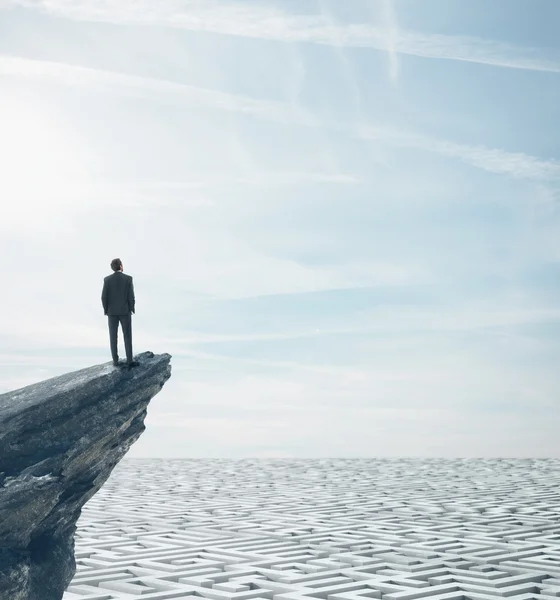 Homme d'affaires debout sur un rocher et regardant labyrinthe énorme — Photo