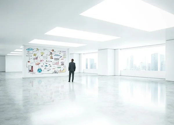 Uomo d'affari in piedi in ufficio vuoto e guardando la strategia di business — Foto Stock