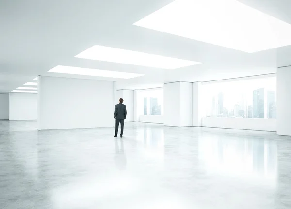 Businessman standing in empty bright office — Stock Photo, Image