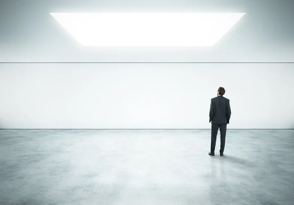 Businessman standing in empty bright office — Stock Photo, Image