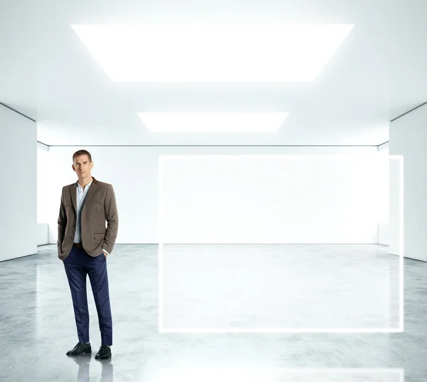 明るいオフィスで立っている青年実業家 — ストック写真