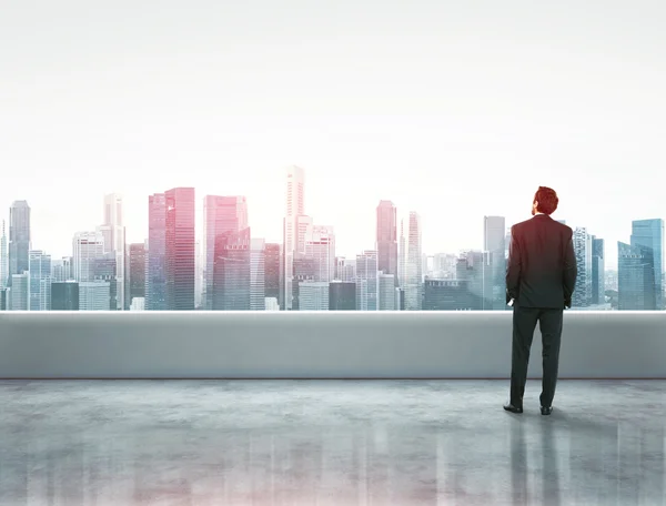 Businessman standing on a roof and looking at city — Stock Photo, Image