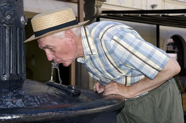 Senior trinkt aus dem Brunnen — Stockfoto