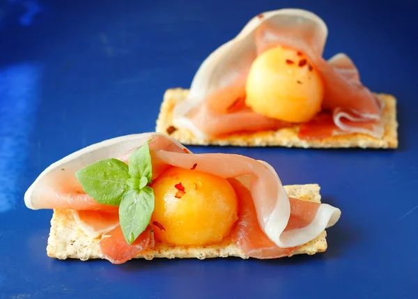 Finger food with melon, prosciutto and crackers — Stock Photo, Image
