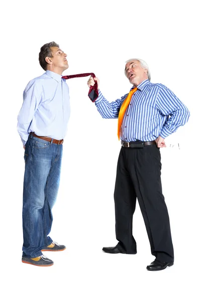 Businessman pulling a tie to younger man — Zdjęcie stockowe