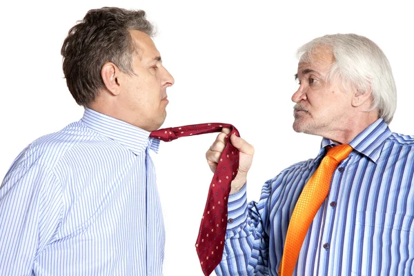 Businessman pulling a tie to younger man Stock Picture
