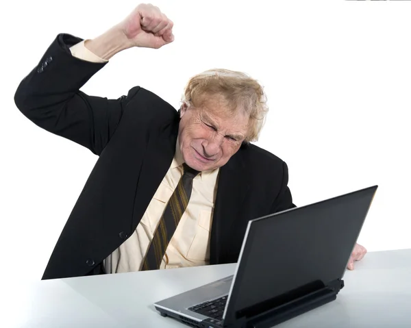 Homme d'affaires en colère assis sur une table avec ordinateur portable — Photo